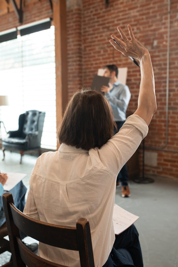 About A student in a classroom raising hand to ask a question. Indoor educational environment.